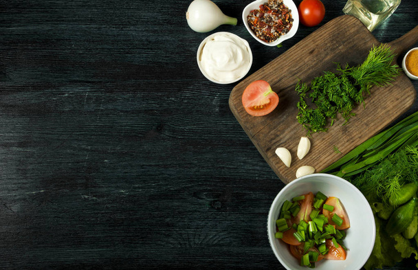 Σαλάτα με λαχανικά. Θέα από πάνω. Φρέσκια σαλάτα σε ένα πιάτο σε σκοτεινό φόντο. Σκόρδο, ντομάτα, αγγούρι, άνηθο και κρεμμύδι σε ένα πιάτο σκοτεινής επιφάνειας. Αντιγραφή χώρου. - Φωτογραφία, εικόνα