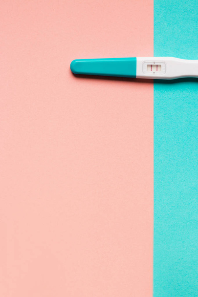 Prueba de embarazo positiva de plástico azul sobre fondo rosa y azul
 - Foto, Imagen