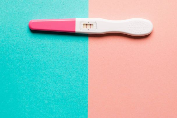 Positivo test di gravidanza in plastica rosa su sfondo rosa e blu
 - Foto, immagini