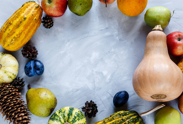 Dzień Dziękczynienia skład warzyw i owoców na szarym tle. Koncepcja jesiennych zbiorów. Dynie, gruszki, śliwki, jabłka na stole, widok z góry, wolne miejsce na tekst - Zdjęcie, obraz