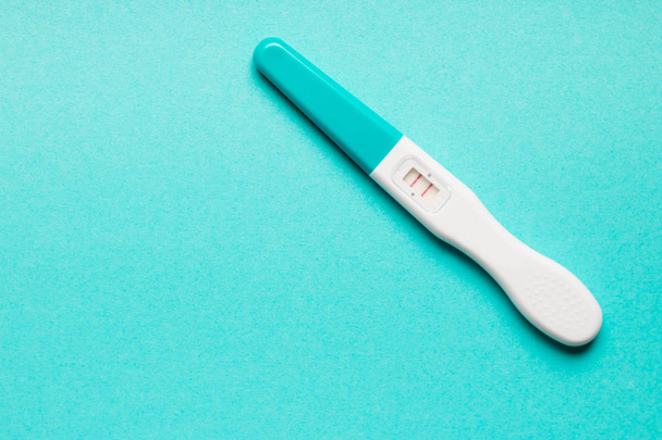 Dodatni niebieski plastikowy test ciążowy na niebieskim tle.  - Zdjęcie, obraz