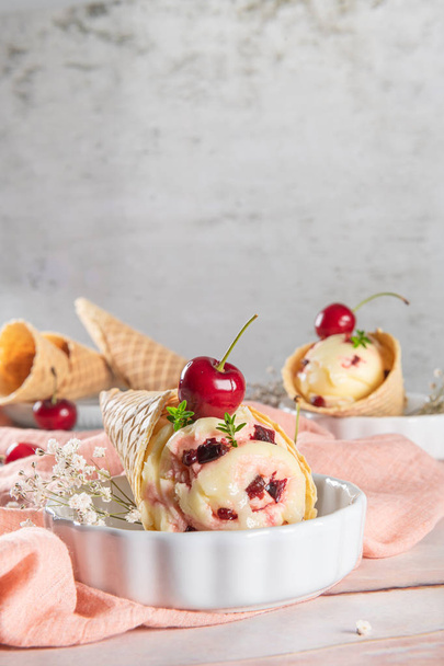 Традиционные вафельные рожки с мороженым и вишневыми фруктами на мраморной поверхности - Фото, изображение