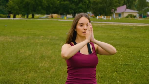 Joven hermosa mujer meditando durante el entrenamiento al aire libre en el parque de verano que se siente la paz. Chica deportiva haciendo yoga al aire libre en la mañana. Movimiento lento
 - Imágenes, Vídeo