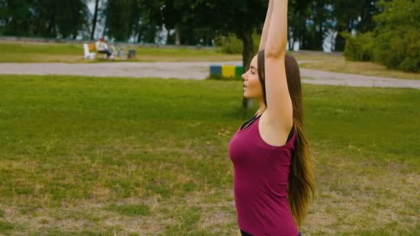 Fiatal szép nő meditál során szabadtéri edzés a nyári parkban érzi a békét. Sportos lány csinál jóga kültéri reggel. Lassított mozgás - Felvétel, videó