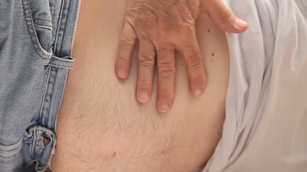 Een man controleert zorgvuldig gebieden waar hij pijn voelt - Video