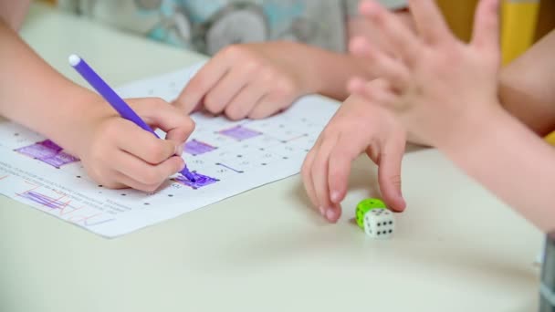 Two kids are playing with two dice and and they are writing something on paper. They are playing a game. - Filmati, video