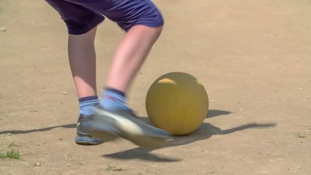 A boy comes and he kicks the yellow soccer ball. Kids are playing soccer outside the school. - Filmmaterial, Video