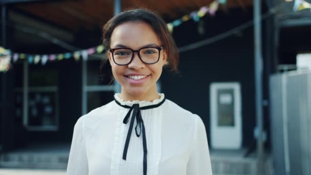 Slow motion portrait of cheerful mixed race girl waving hand smiling outdoors - Materiał filmowy, wideo