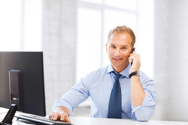 Smiling businessman with smartphone in office - Foto, afbeelding