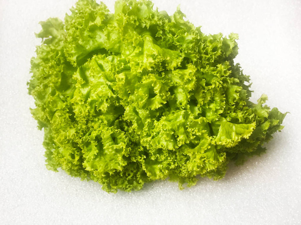 Kasa lehtiä vihreää kiharaa salaattia valkoisella taustalla. Lähemmäs. Eristetään
 - Valokuva, kuva