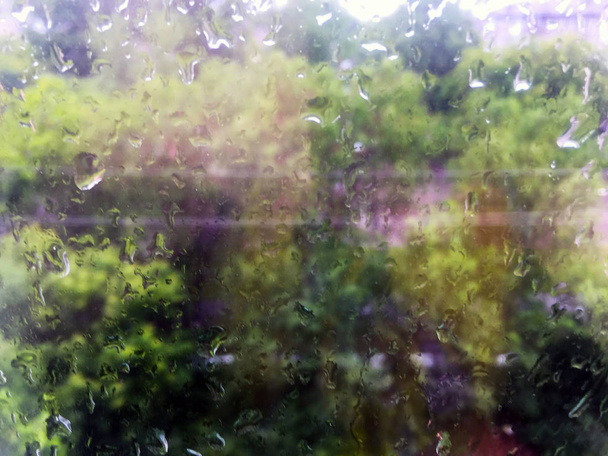 Tropfen vom Regen auf das Glas. grüne Bäume vor dem Fenster. - Foto, Bild