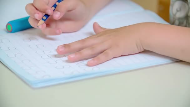Een leerling oefent hoe een letter s in haar werkboek te schrijven. Ze schrijft het woord s vele malen in rijen. - Video