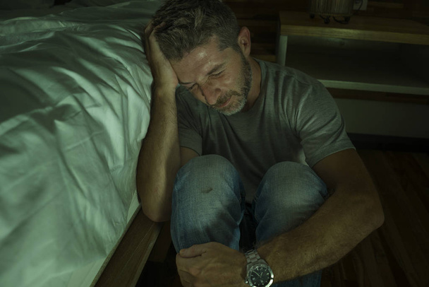 dramatic home portrait of young desperate and depressed lonely man sitting on bedroom floor crying sick suffering anxiety crisis and depression problem feeling helpless - Foto, afbeelding