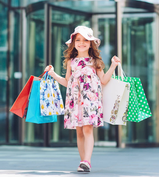 Мила маленька дівчинка на шопінгу. Портрет дитини з сумками. Шопінг. дівчина
. - Фото, зображення