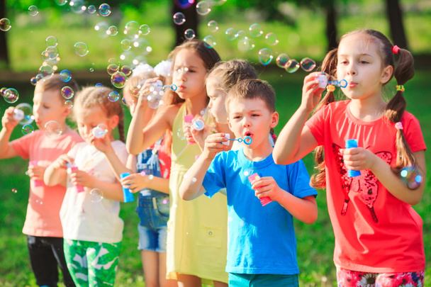 Група дітей, які дмуть мильні бульбашки
. - Фото, зображення