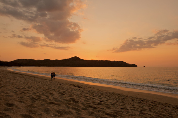 Coppia a piedi sulla spiaggia al tramonto. - Foto, immagini