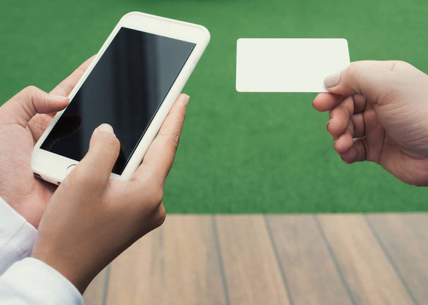 Руки крупным планом женщины держат кредитную карту и с помощью мобильного телефона, интернет-магазинов, на открытом воздухе
 - Фото, изображение