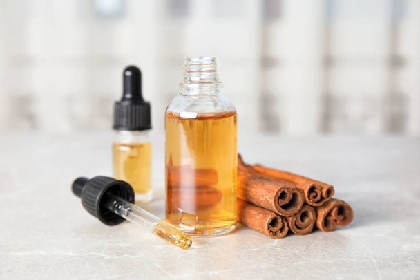Bottles of essential oils and cinnamon sticks on grey marble table - Foto, imagen