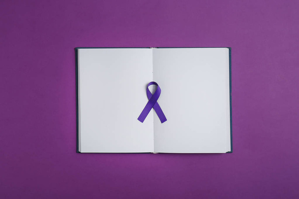Purple awareness ribbon and open notebook on color background, top view - Φωτογραφία, εικόνα