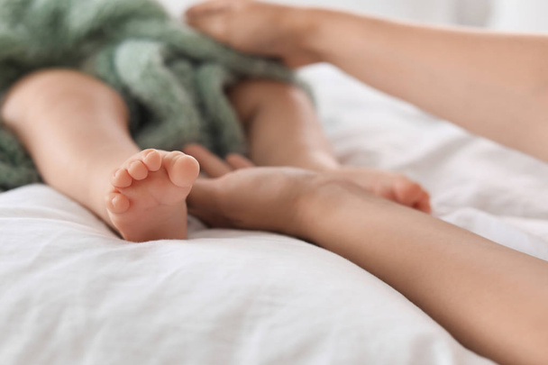 Mother holding feet of her little baby on bed, closeup - Φωτογραφία, εικόνα