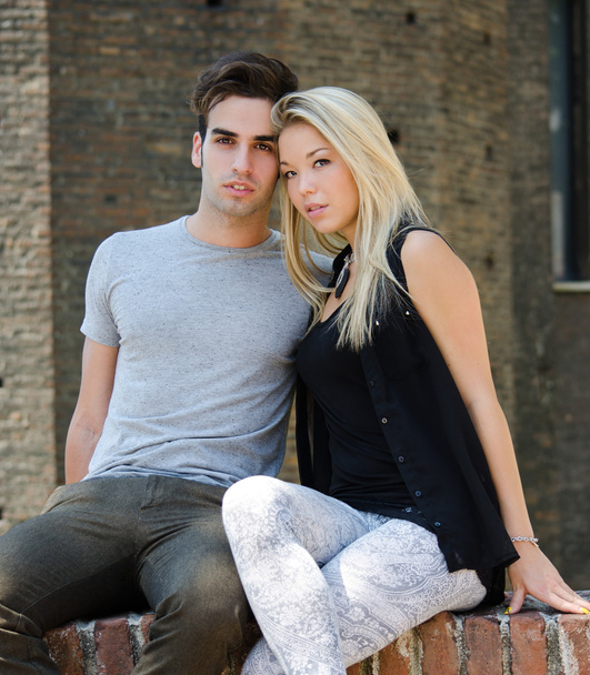 Attractive couple sitting and leaning against one another - Photo, image