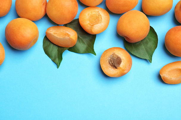 Delicious ripe sweet apricots on blue background, flat lay. Space for text - Photo, Image