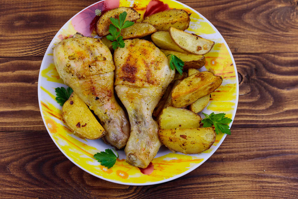 Ψητά κοτόπουλα με πατάτες σε ένα πιάτο σε ξύλινο τραπέζι - Φωτογραφία, εικόνα