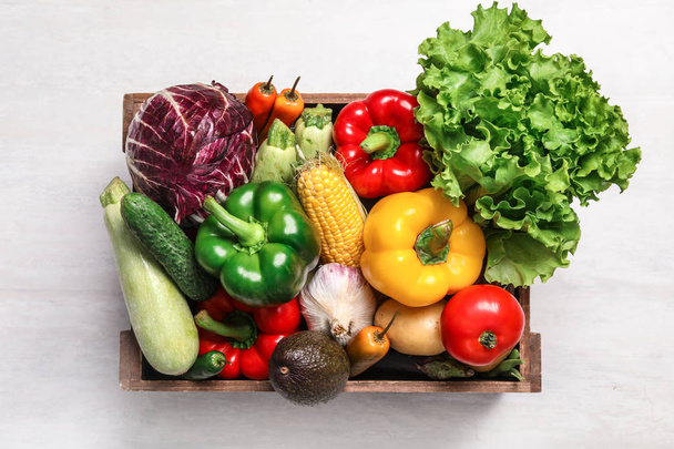 Crate with different fresh vegetables on light background, top view - Фото, изображение