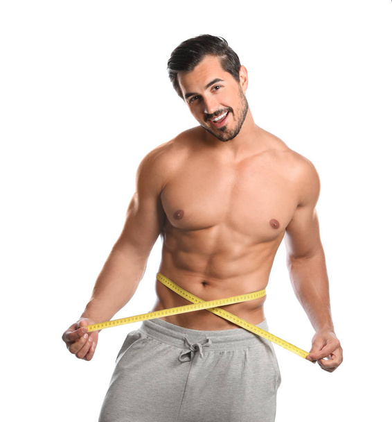 Young man with slim body using measuring tape on white background - Photo, image