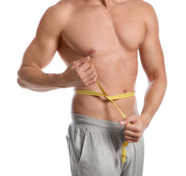 Young man with slim body using measuring tape on white background, closeup view - Valokuva, kuva