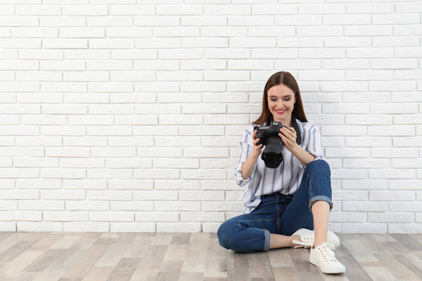 Professional photographer with modern camera near white brick wall. Space for text - Photo, Image