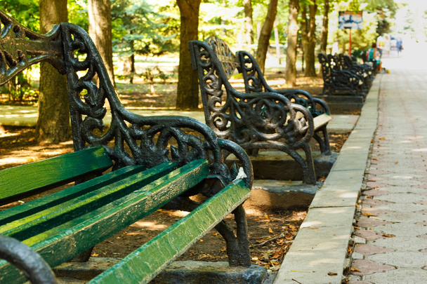 Παλιό παγκάκι σε ένα σοκάκι σε ένα καταπράσινο πάρκο της πόλης - Φωτογραφία, εικόνα