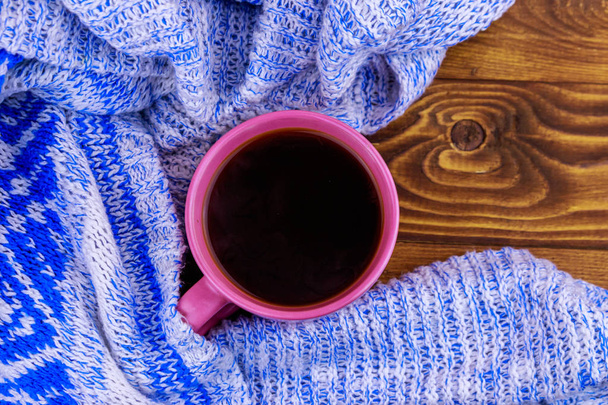 Šálek kávy a útulný pletený svetr na dřevěném stole - Fotografie, Obrázek