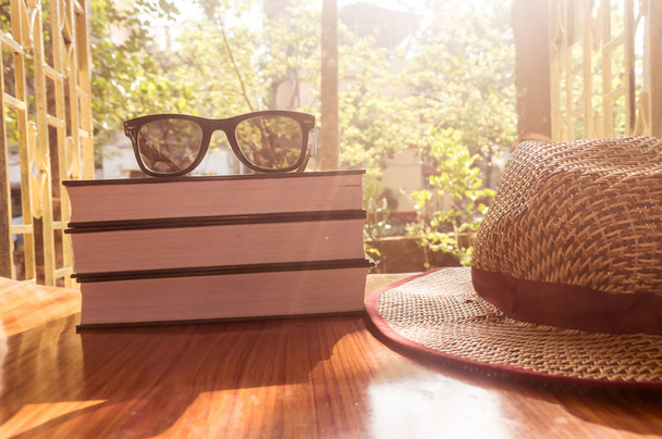 Vista frontal del libro y gafas de sol con sombrero de paja. Vacaciones de verano concepto de fondo
. - Foto, Imagen