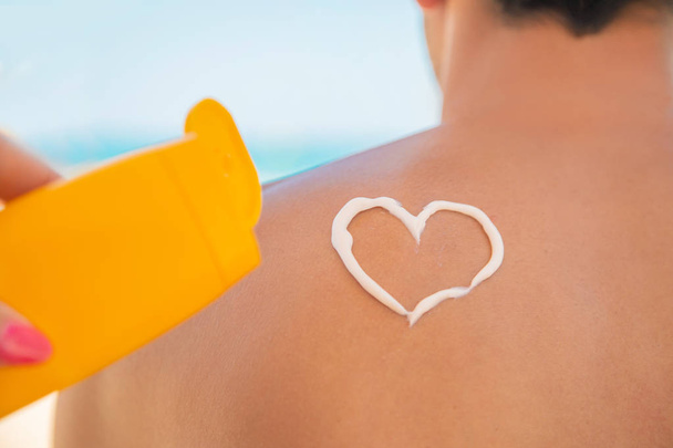 The girl on the beach applies sunscreen to the skin of a man. Selective focus. - Fotó, kép