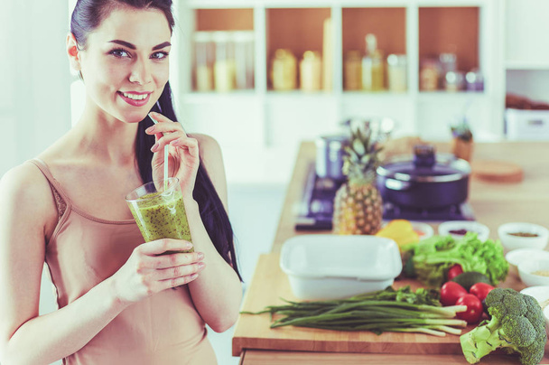 Young woman with glass of tasty healthy smoothie at table in kitchen - Foto, imagen