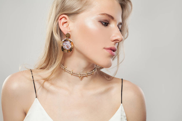 Gold jewelry model. Beautiful blonde woman with golden earrings  - Photo, image