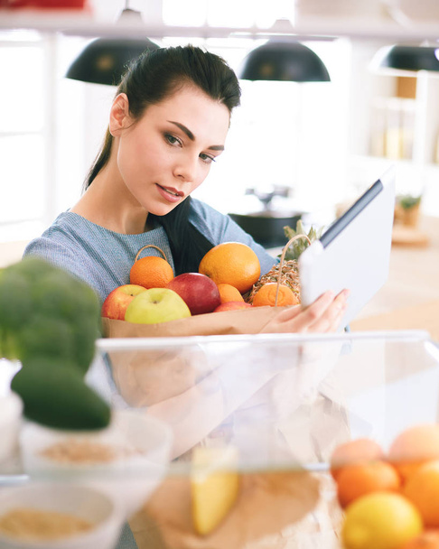 Smiling woman taking a fresh fruit out of the fridge, healthy food concept - Foto, Bild