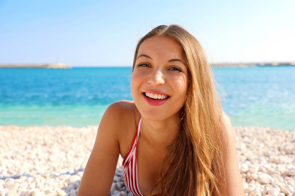 Happy beautiful cheerful smiling woman enjoying relax lying on the beach looking at camera. Summer holidays concept. - Zdjęcie, obraz