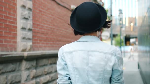 Mouvements lents de la jeune femme marchant à l'extérieur puis tournant clin d'oeil touchant chapeau
 - Séquence, vidéo