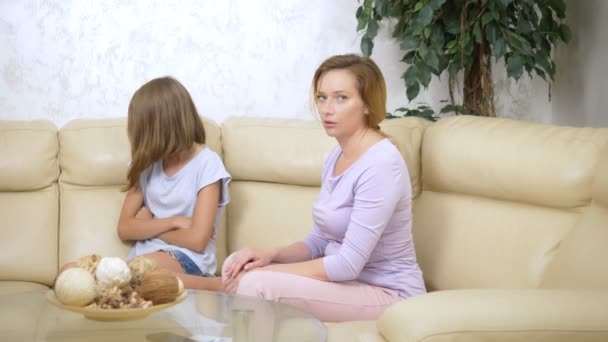 disappointed mother reprimands her daughter, who ignores her, sitting on the sofa in the living room - Filmati, video