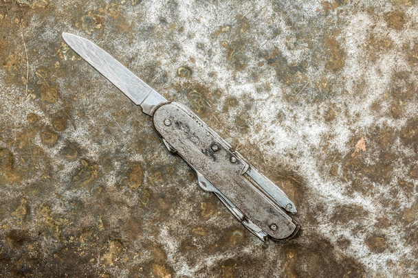 old folding knife on old rumpled shabby metal, close-up abstract background - Foto, imagen
