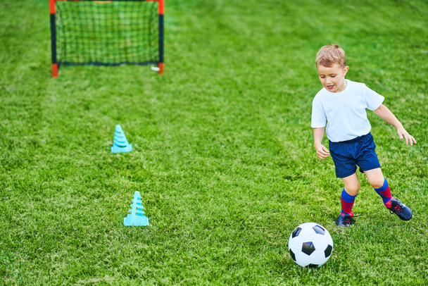 Menino praticando futebol ao ar livre
 - Foto, Imagem