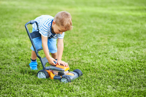Heureux garçon de 3 ans ayant plaisir à tondre la pelouse
 - Photo, image