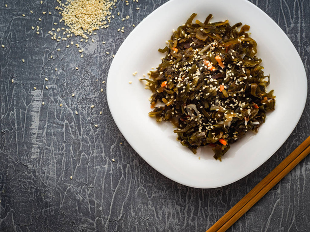 Seaweed salad with sesame seeds is on a white plate - Photo, Image