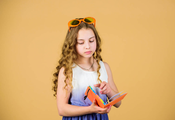 small happy girl in glasses with notebook. small beauty girl write her memories. diary notes. reading book. Summer fashion. making plans for summer holidays and vacation. student read book - Фото, изображение