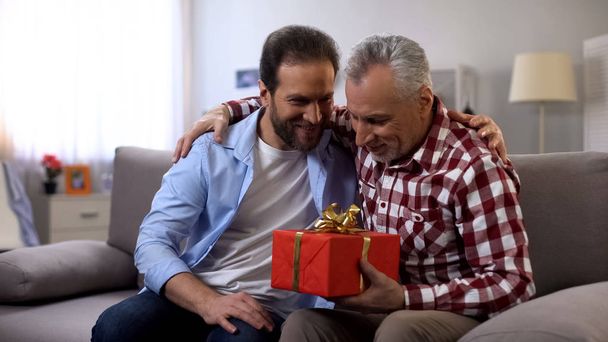 Son and father embracing, male holding gift box, receiving greetings, birthday - Fotografie, Obrázek