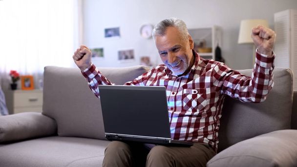 Cheerful elderly man getting answer on dating site, receiving good news, luck - Fotó, kép