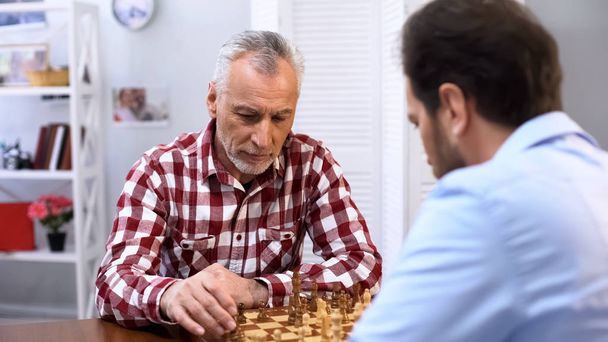 Serious senior male playing chess with opponent, complicated competition, sport - Photo, image