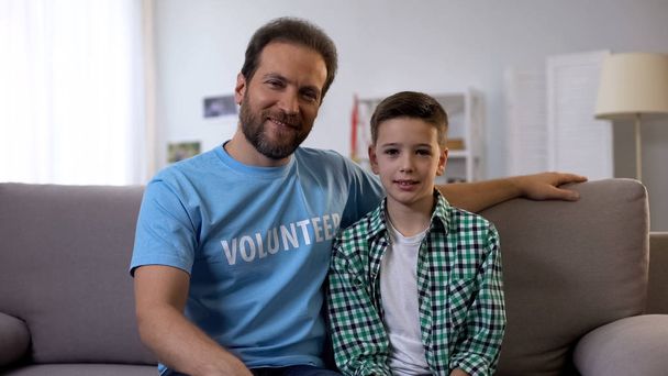 Volunteer and boy sitting on coach, global helping program to support orphans - Foto, Bild